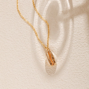 Gros plan sur le collier pendentif coquillage doré avec incrustation blanche nacrée