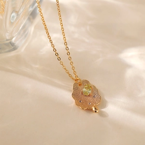 Dettaglio macro del ciondolo a fiore in oro 18K con zircone giallo e finitura strutturata
