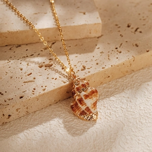 Vue macro du pendentif en coquillage naturel avec dorure et détail de chaîne dorée