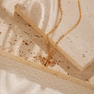 Gros plan détaillé d'un pendentif abeille plaqué or sur une fine chaîne élégante