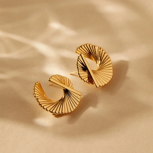 French vintage style twisted fan-shaped earrings plated in 18K gold on beige background