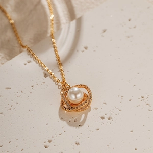Gros plan détaillé du collier à anneaux dorés entrelacés avec perle blanche et zircons fins