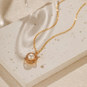 Détail d'un collier de perles dorées avec pendentif double couche serti de oxydes de zirconium