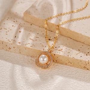 Gros plan d'un pendentif perle ronde avec oxydes de zirconium sur collier chaîne dorée