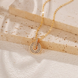 Gros plan d'un collier doré avec pendentif serti de pierres sur un fond en pierre texturé