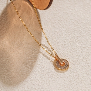 Détail d'un collier doré avec pendentif rond serti de zircons brillants et élégants