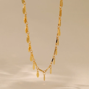 Primer plano detallado de un collar de doble capa chapado en oro de 18K con dijes de hojas