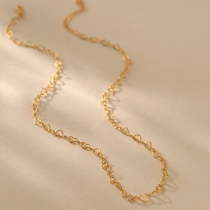 Detalle de primer plano de un collar bañado en oro con pequeños eslabones de corazón