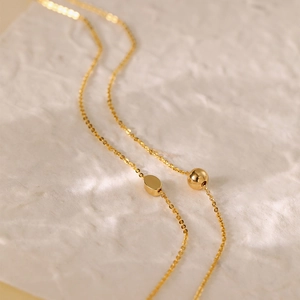 Minimalist 18K gold plated necklace featuring smooth oval pendant and sphere charm details