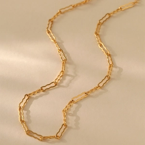 Primer plano de un collar minimalista chapado en oro con eslabones rectangulares ondulados