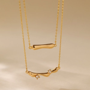 Detail of 18K gold plated double layer necklace with fluid pendant and zircon stones