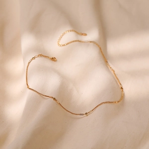 Detalle del collar de cadena fina bañada en oro con delicados colgantes de diamantes