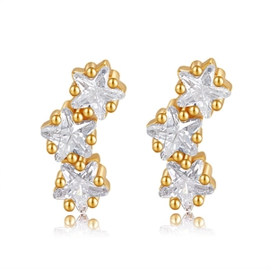 Détail de boucles d'oreilles triple étoile dorées avec cristaux de zircone brillants