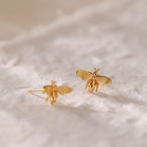 Macro de boucles d'oreilles abeilles dorées avec ailes polies et détails raffinés