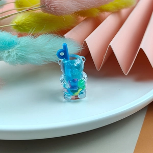 Gros plan d'une breloque tasse d'ours en résine bleue avec des perles colorées