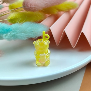 Gros plan d'une breloque ours jaune en résine pour bijoux DIY avec détail de paille