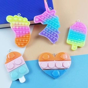 Rainbow silicone pop-it keychains in unicorn, heart, and ice cream shapes with rings