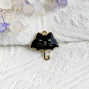 Close-up of black enamel cat umbrella pendant charm for DIY jewelry with gold metal edges