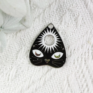 Vue macro du pendentif chat noir planchette avec soleil et lune en émail pour bijoux DIY