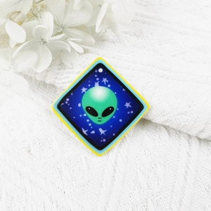 Vue détaillée d'un pendentif extraterrestre en acrylique sur un fond en tissu tricoté blanc