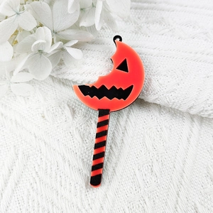 Macro view of Halloween pumpkin moon acrylic charm on white knitted background