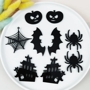 Détail de breloques d'Halloween en acrylique noir avec motifs araignées et citrouilles