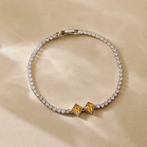Exquisite silver-toned tennis bracelet with yellow square zircon center on beige texture