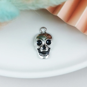 Macro view of a silver skull pendant with black enamel details and fixed hanging loop