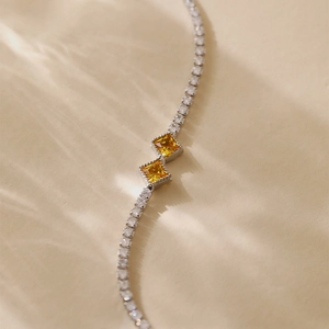 Elegant silver bracelet with zircon crystals and yellow square gemstones in artistic light