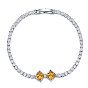 Close-up of silver tennis bracelet with clear rhinestones and two yellow square zircons