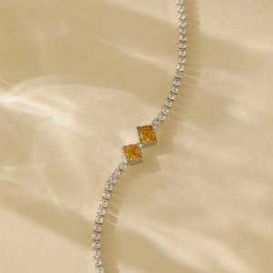 Detail view of silver tennis bracelet featuring two yellow square zircon focal stones