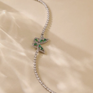 Detail of silver bracelet with green zircon butterfly charm and shimmering crystals