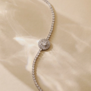 Macro shot of silver tennis bracelet featuring a brilliant round center stone and pave zircon