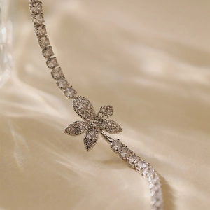Macro shot of silver-tone flower bracelet with cubic zirconia on silk with soft shadows