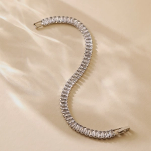 Detail of silver tennis bracelet with rectangular zircons on soft cream fabric