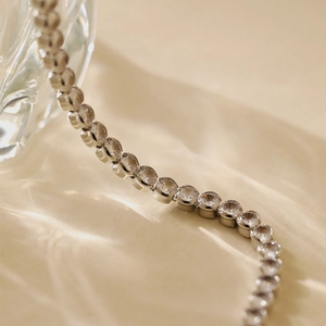 Macro shot of a silver floral tennis bracelet with sparkling cubic zirconia on silk fabric
