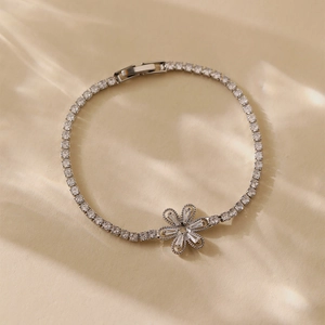 Detailed view of silver flower bracelet with cubic zirconia on a textured background