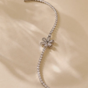 Macro shot of silver-colored flower bracelet with zircons and sleek S-shaped chain link