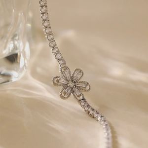 Macro shot of silver floral tennis bracelet with cubic zirconia on satin background
