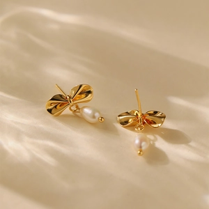 Elegant 18K gold bow freshwater pearl earrings on silk fabric with soft lighting