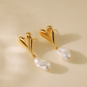 Elegant gold heart earrings with white baroque pearls shown in a soft studio lighting view