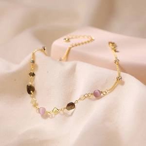 Detalle de la tobillera bohemia dorada con cuentas de ojo de gato rosa y piedras naturales