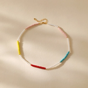 Boheemse parelketting met gekleurde kralen en gouden sluiting op beige achtergrond