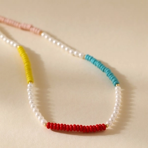 Boheemse parelketting met kleurrijke turquoise kralen en gouden accenten op textuurachtergrond