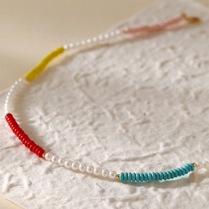 Boheemse parelketting met kleurrijke kralen en gouden accenten op getextureerd papier