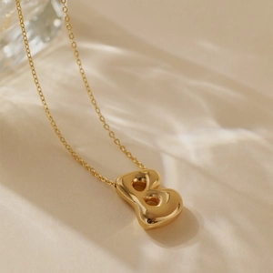 Macro shot of gold plated puffy letter B pendant on a delicate cable chain necklace
