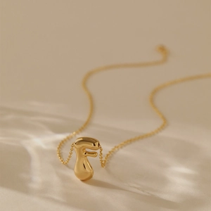 Macro shot of 18K gold plated letter F pendant necklace with a high-polished mirror finish
