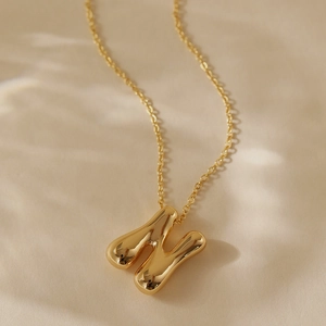 Detail of 18k gold plated 3D puffed letter H pendant with mirror polish on cable chain