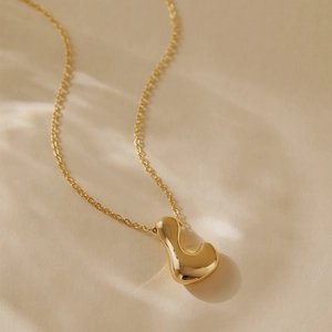 Detailed close-up of a polished gold letter J pendant necklace with delicate chain