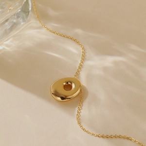 Detail shot of the irregular gold hollow circular pendant and fine cross chain necklace